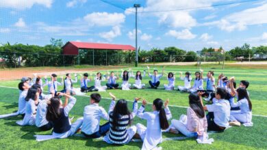 people sitting on green lawn grass while doing hands up at daytime